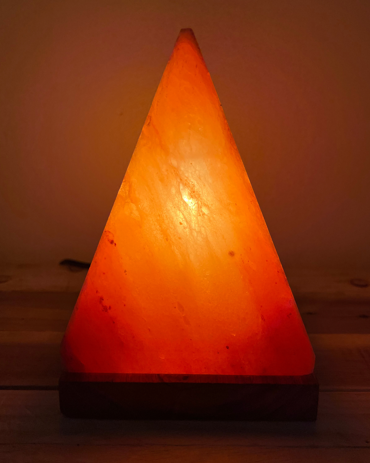 Handgemaakte Himalaya zoutlamp piramidevorm met houten voet en warme gloed