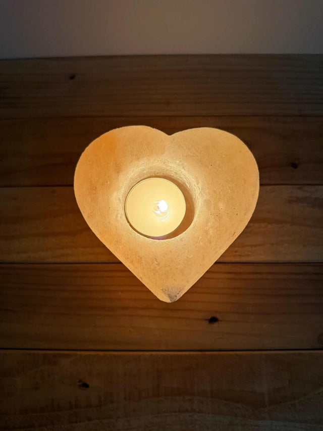 Handgemaakte hartvormige waxinelichthouder van natuurlijke zoutsteen met warm oranje gloed
