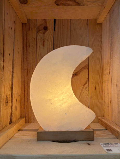 Himalaya zoutlamp in maanvorm in roze, grijs en wit met zachte, rustgevende gloed en houten voet.