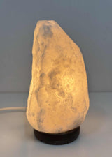 Brandende Himalaya zoutlamp grijs 2-3 kg met warme gloed op houten voet